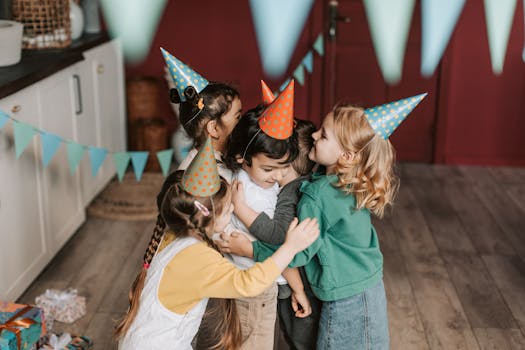 Children wearing party hats embrace each other during a joyful indoor birthday celebration.